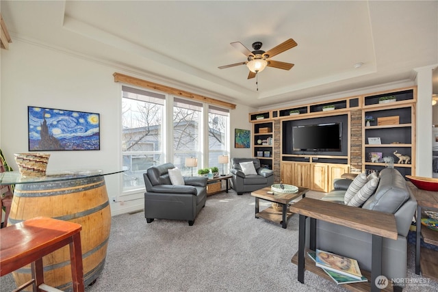 living room featuring a raised ceiling, crown molding, light colored carpet, and ceiling fan