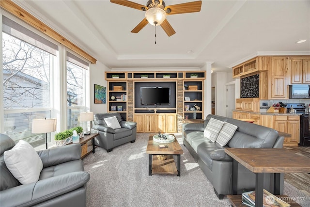 living room with crown molding, a tray ceiling, light colored carpet, and ceiling fan