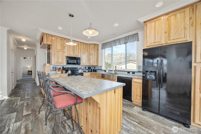 kitchen with crown molding, decorative light fixtures, black appliances, and a center island