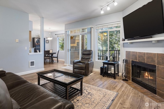 living room featuring a tiled fireplace and hardwood / wood-style floors