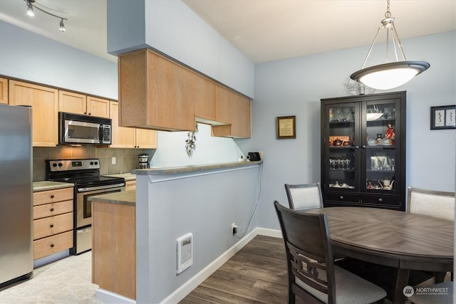 kitchen featuring pendant lighting, dark wood-type flooring, appliances with stainless steel finishes, backsplash, and kitchen peninsula