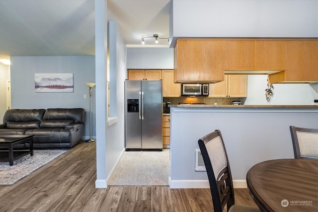 kitchen featuring appliances with stainless steel finishes, dark hardwood / wood-style flooring, kitchen peninsula, and backsplash