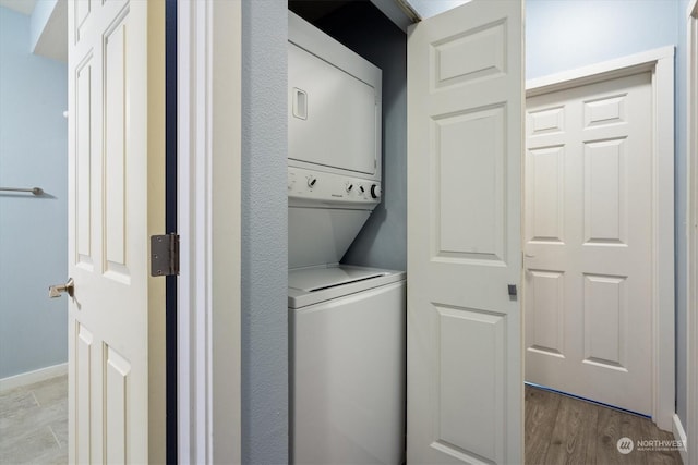 laundry room with stacked washer and dryer and light hardwood / wood-style floors