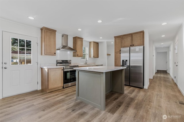 kitchen with light hardwood / wood-style floors, wall chimney range hood, stainless steel appliances, and a center island