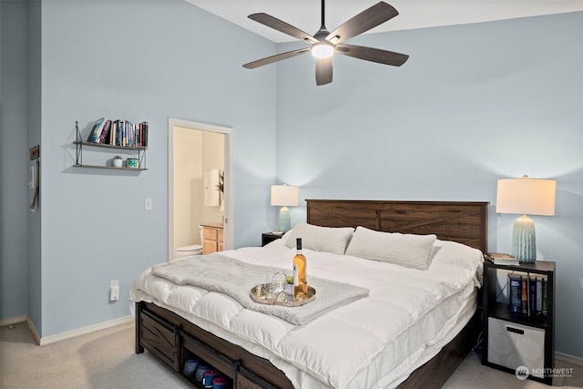 bedroom with ceiling fan, light colored carpet, ensuite bath, and a towering ceiling