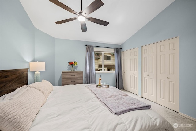 bedroom featuring multiple closets, lofted ceiling, carpet flooring, and ceiling fan