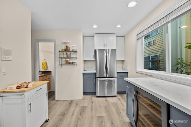 kitchen featuring gray cabinetry, white cabinets, stainless steel fridge, beverage cooler, and light hardwood / wood-style flooring