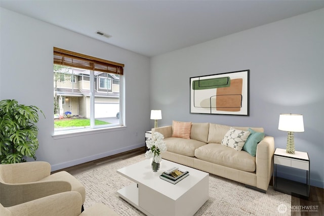 living area with wood finished floors, baseboards, and visible vents