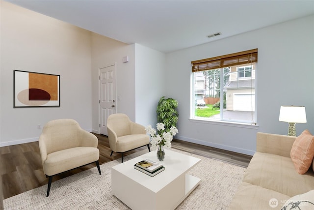 living room with visible vents, baseboards, and wood finished floors