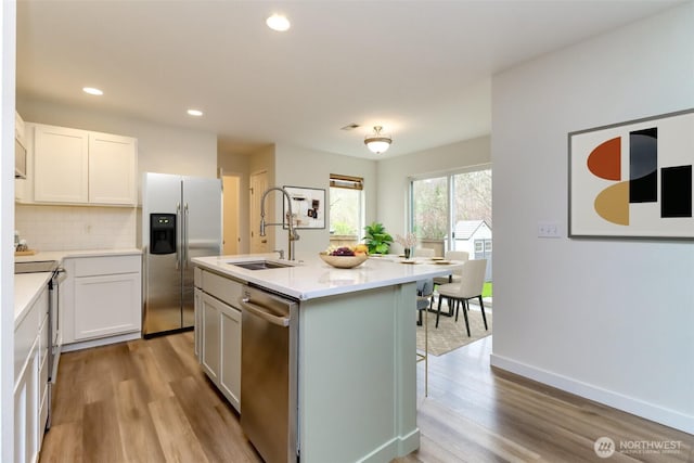 kitchen with tasteful backsplash, appliances with stainless steel finishes, wood finished floors, and a sink