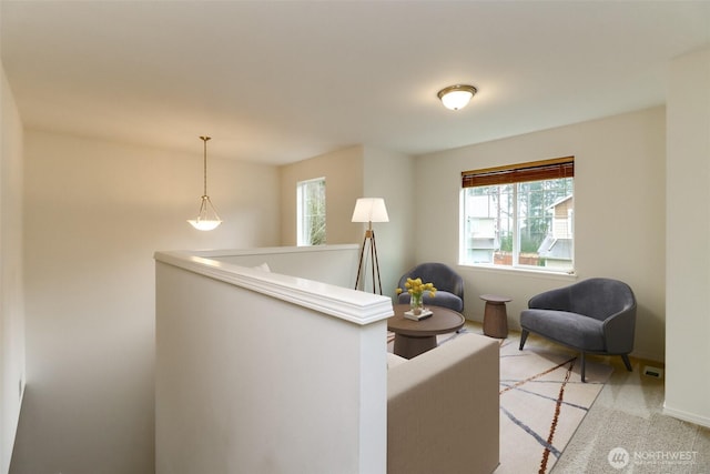 living area featuring baseboards, an upstairs landing, and light colored carpet