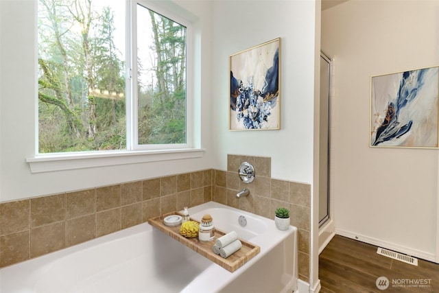full bathroom with a shower with shower door, visible vents, a garden tub, and wood finished floors