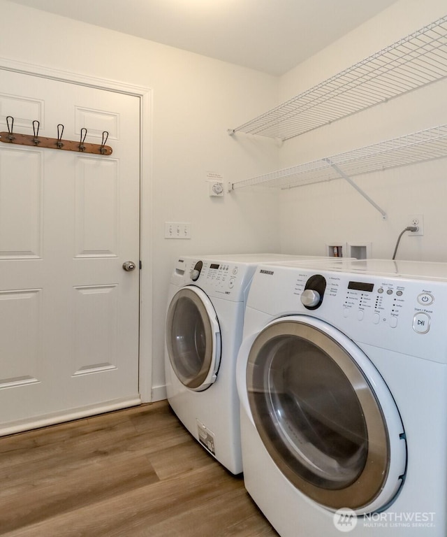 clothes washing area featuring laundry area, washing machine and clothes dryer, and light wood-type flooring