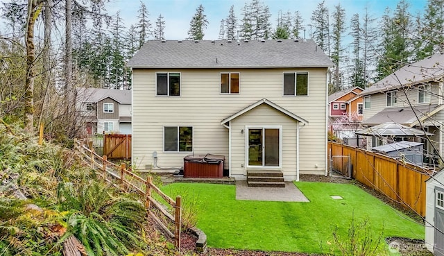 rear view of property featuring a patio, entry steps, a fenced backyard, a hot tub, and a lawn