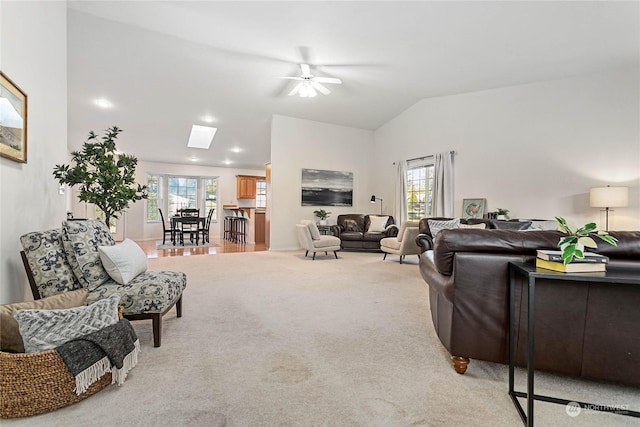 carpeted living room with vaulted ceiling with skylight and a wealth of natural light