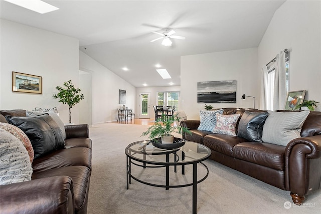 carpeted living room featuring ceiling fan and lofted ceiling with skylight