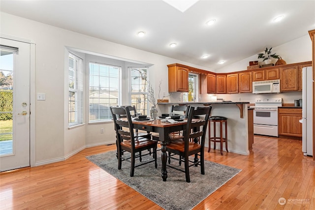 dining area featuring vaulted ceiling, a healthy amount of sunlight, and light wood-type flooring