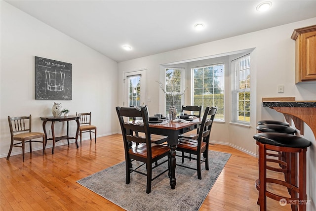 dining space with vaulted ceiling and light hardwood / wood-style flooring