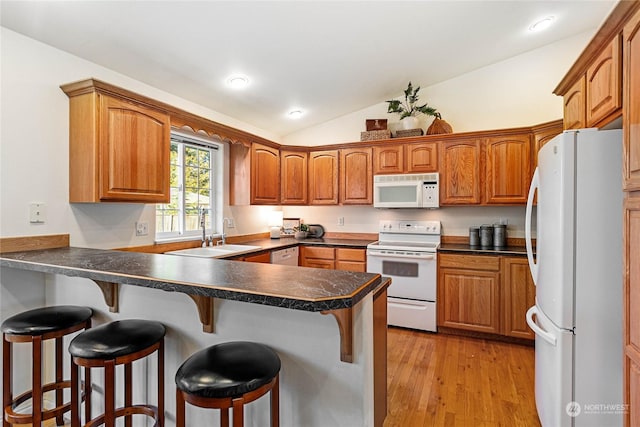 kitchen with vaulted ceiling, a breakfast bar, sink, kitchen peninsula, and white appliances