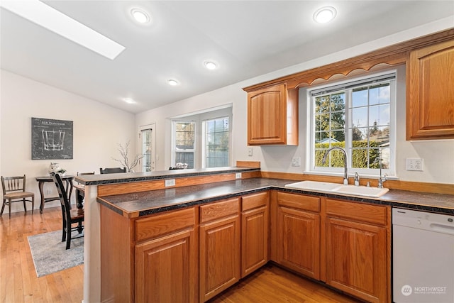 kitchen featuring vaulted ceiling, sink, white dishwasher, kitchen peninsula, and plenty of natural light