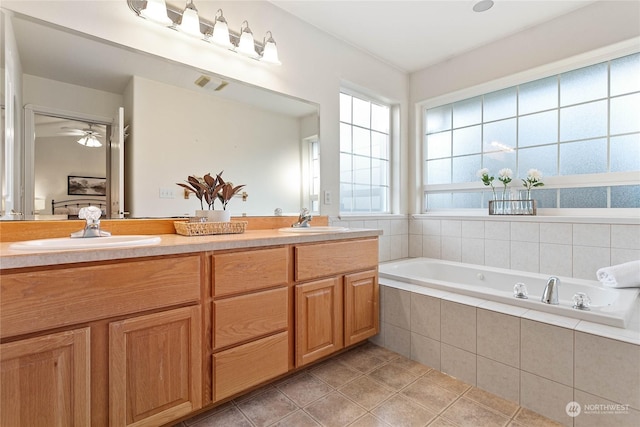 bathroom with vanity, a relaxing tiled tub, and tile patterned floors