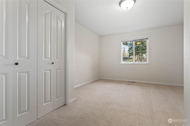 unfurnished bedroom featuring light colored carpet and a closet