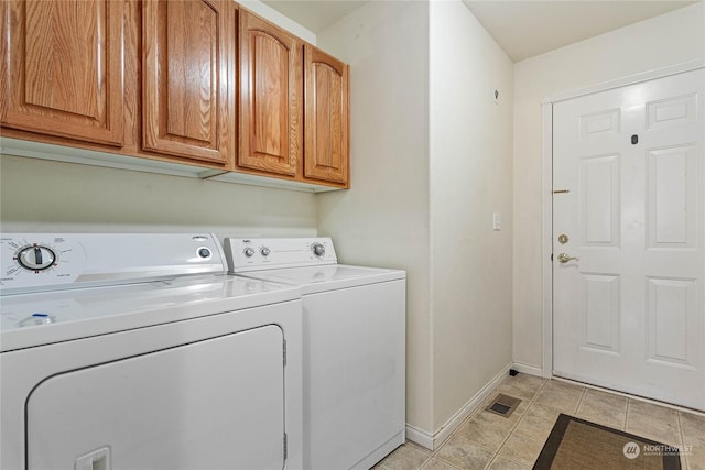 washroom featuring cabinets, washing machine and dryer, and light tile patterned floors