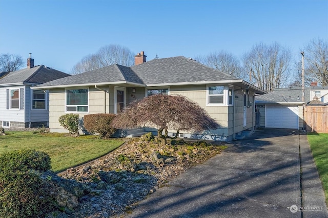 view of front of property with a garage, an outbuilding, and a front lawn