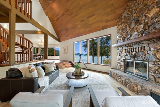 living room featuring light hardwood / wood-style flooring, high vaulted ceiling, a water view, a notable chandelier, and a fireplace