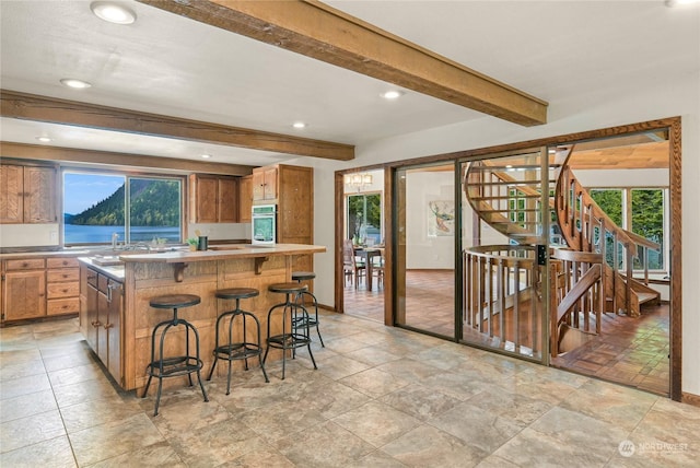 kitchen featuring beamed ceiling, a kitchen island, a breakfast bar area, and oven