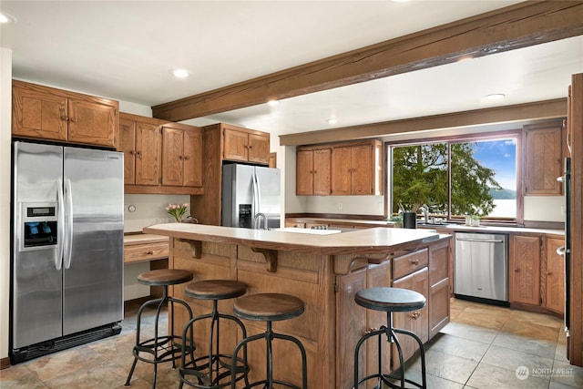 kitchen featuring a kitchen island, a breakfast bar area, beamed ceiling, and appliances with stainless steel finishes