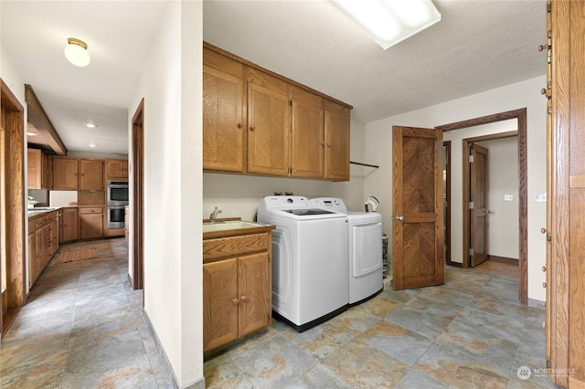 laundry area with sink, washer and clothes dryer, and cabinets