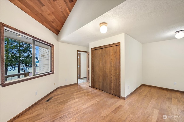 unfurnished bedroom featuring vaulted ceiling, wood ceiling, light wood-type flooring, and a closet