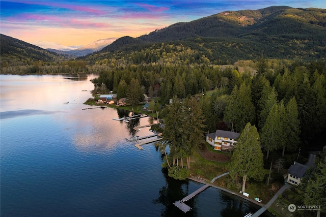 aerial view at dusk featuring a water and mountain view