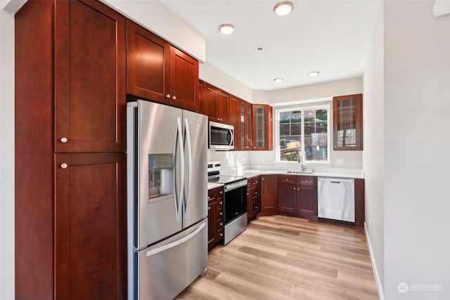 kitchen featuring stainless steel appliances, sink, and light hardwood / wood-style floors