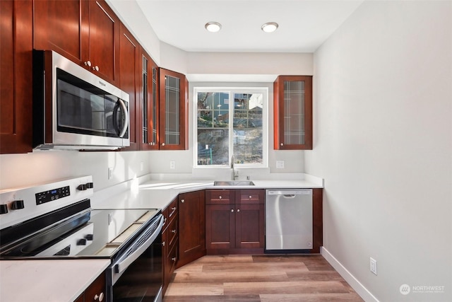 kitchen with stainless steel appliances, sink, and light hardwood / wood-style floors