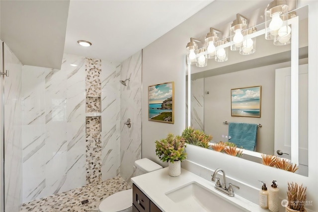 bathroom with vanity, a tile shower, and toilet