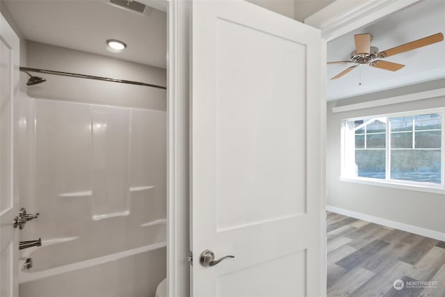 bathroom with hardwood / wood-style floors, tub / shower combination, and ceiling fan