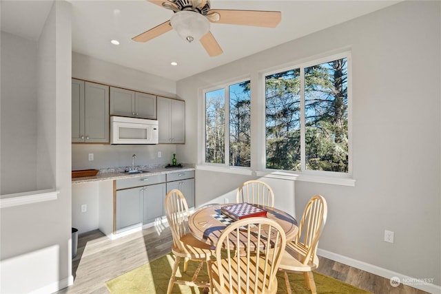 dining room with ceiling fan, sink, and light wood-type flooring