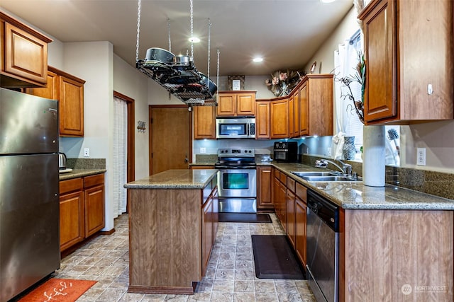 kitchen featuring appliances with stainless steel finishes, a center island, sink, and dark stone counters