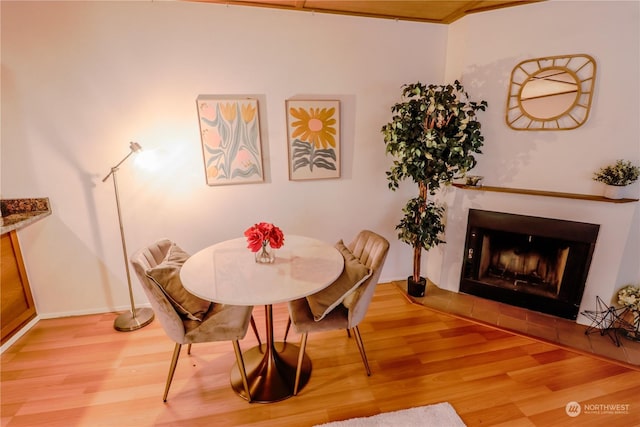 dining area with wood-type flooring and a tile fireplace