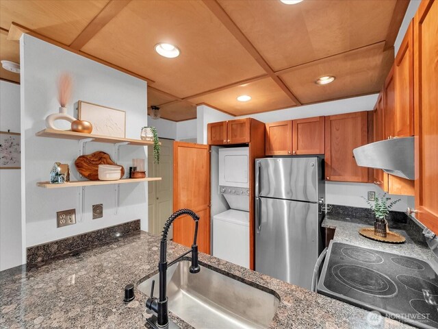 211 Summit Ave E Unit N308, Seattle, WA 98102 - kitchen featuring freestanding refrigerator, stacked washing machine and dryer, range hood, brown cabinetry, and range