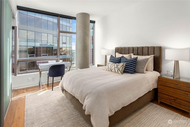 bedroom with multiple windows, floor to ceiling windows, and light hardwood / wood-style floors