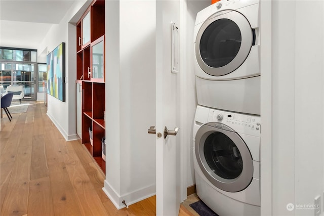 clothes washing area featuring stacked washer and clothes dryer and light wood-type flooring