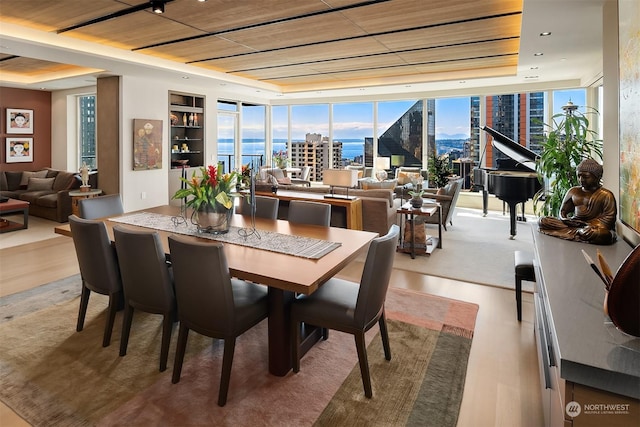 dining area featuring a raised ceiling, expansive windows, and hardwood / wood-style flooring