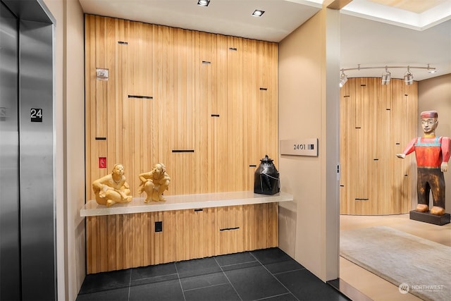 mudroom with dark tile patterned flooring, track lighting, and elevator