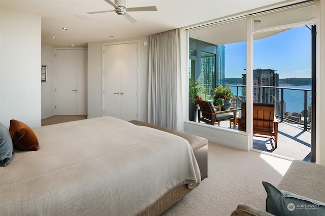 bedroom with a water view, carpet flooring, a closet, ceiling fan, and access to exterior