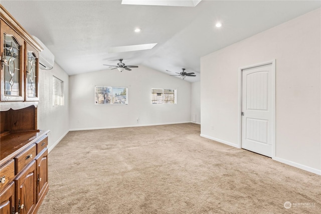 unfurnished living room with light carpet, plenty of natural light, vaulted ceiling with skylight, and ceiling fan