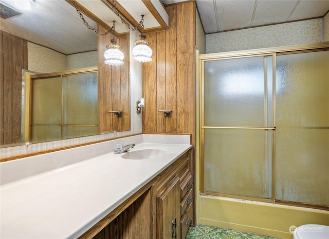 full bathroom featuring vanity, combined bath / shower with glass door, wooden walls, and toilet