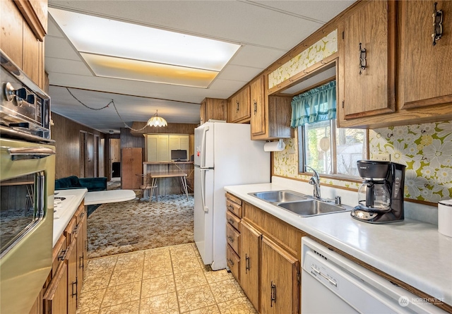 kitchen with pendant lighting, white appliances, and sink